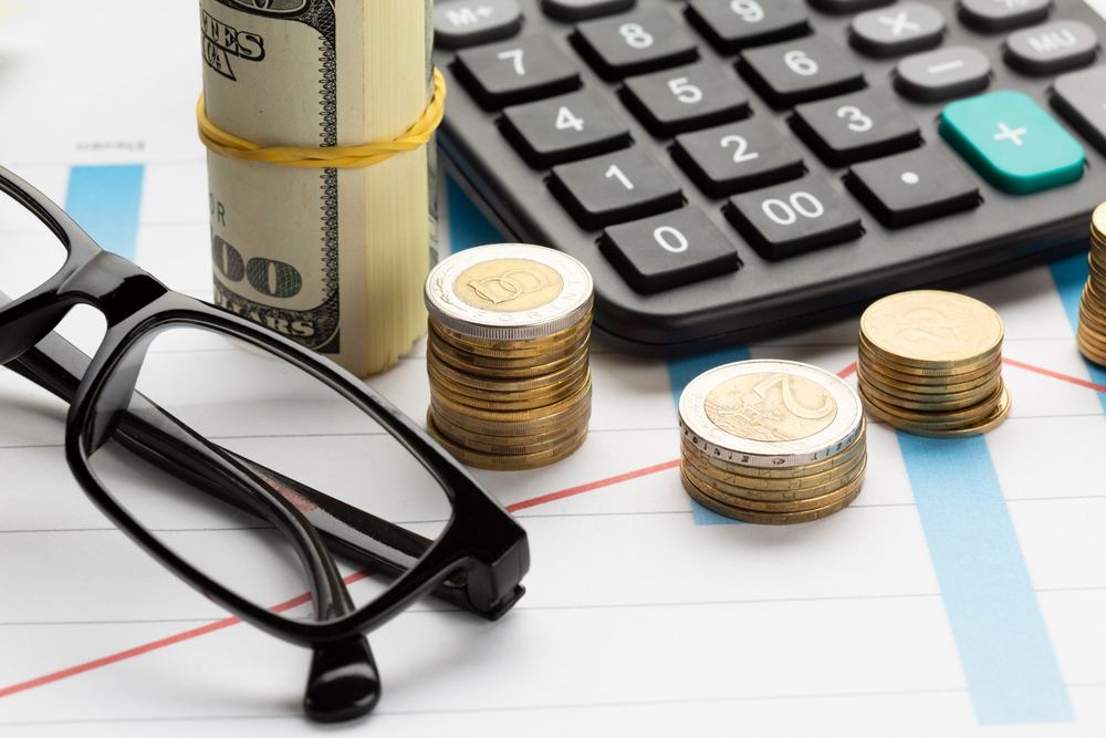 Reading glasses, coins and a calculator on a printed chart